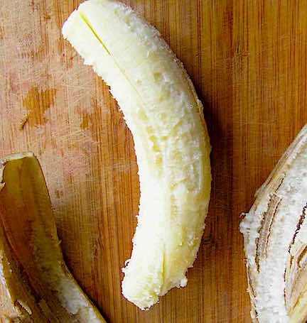 A peeled, over ripe banana on a wooden cutting board.