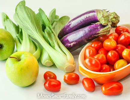 Colorful produce on a table, including apples, tomatoes, eggplant and bok chow.