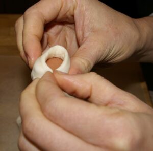 Pork Main Dish Recipes (Ham and Sausage too) – Delicious to Eat! 10 Two hands wrapping dough around a cut up hot dog.