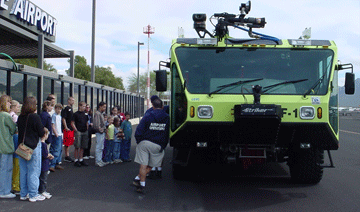 A green fire truck at an airport field trip for students.