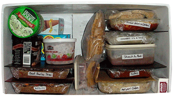 Several frozen meals stacked in glass baking dishes in a refrigerator freezer.