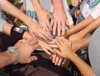 A baseball team putting hands together in a circle before the game.