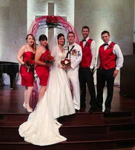 A bridal party dressed in red and white standing on a church platform.