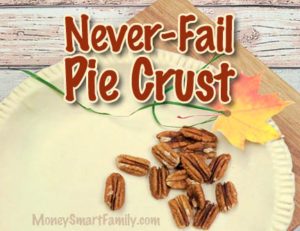 A pie crust sitting on a wooden cutting board with pecans and autumn leaves sitting on it.