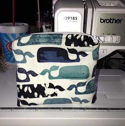 A zippered pouch with Whale pattern sitting on a sewing machine.