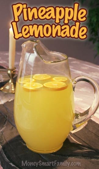 A glass pitcher full of pineapple lemonade with lemons floating on top.