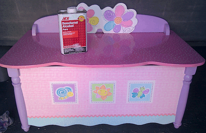 Pink and lavender toy chest with a can of denatured alcohol on it.