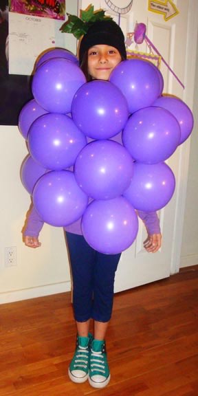 10 DIY Non-Scary Halloween Costumes that are Easy, Cheap & Fast 4 A girl with purple balloons on her body, dressed as a cluster of grapes.
