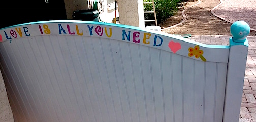 An old headboard with the words "love is all you need" painted on it.