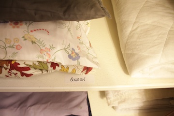 Linen Closet Organization Hacks: 9 Brilliant Tips, Tricks and Ideas 2 Bed linens and a bed pad stacked on a linen closet shelf.