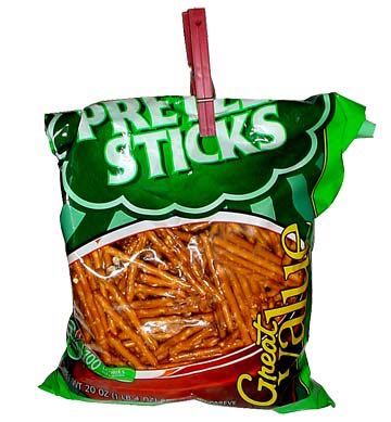 A green pretzel bag with a red clothes pin on it.