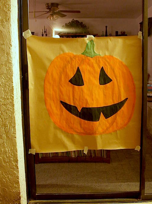 A DIY pin the nose on the pumpkin game painted on brown kraft paper.