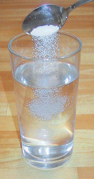 A clear glass with warm salt water for gargling.
