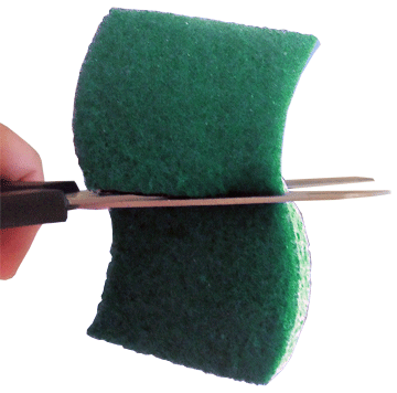 Sponge being cut in half with scissors.