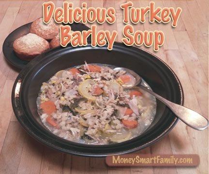 Turkey-Barley-Soup-Horiz A black bowl filled with turkey barley soup and 3 cornbread muffins on another dish.