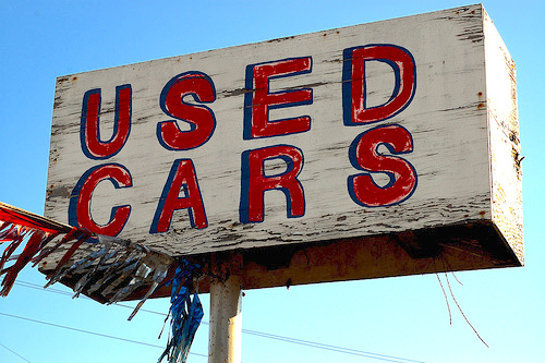 An old wooden Used Cars dealer sign.