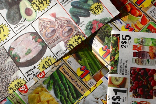 14 New Grocery Shopping Tips to Help Survive a World-Wide Pandemic 1 Several grocery ads in a pile on the counter.