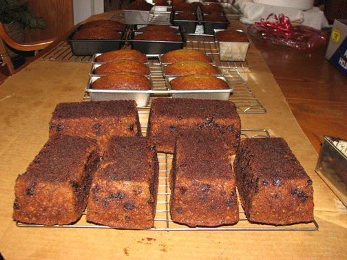 Eight loaves of chocolate chip banana bread hot from the oven sitting on cooling racks.