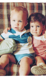 two toddler boys sitting on a plaid couch
