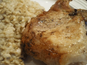 A pork chop sitting on a plate with rice.