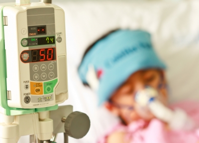 A child in a hospital bed with an oxygen mask on his face.