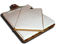 A clipboard and a smaller scratch pad made from scrap, recycled paper.