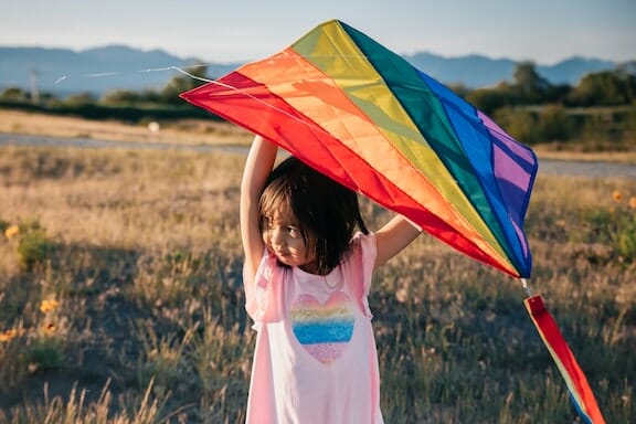 A young girl holding a colorful kite with her family.